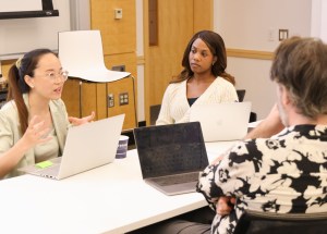 Three participants sitting at a table while one talks to the others.
