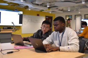 Two participants sitting at a table and looking at a laptop screen together.